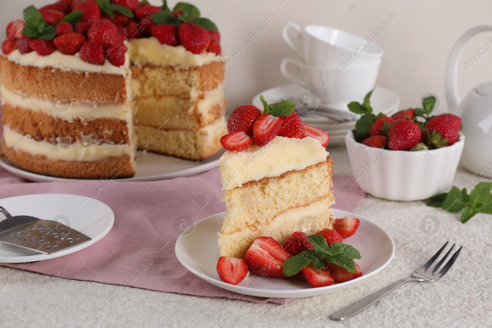 Photo of Piece of tasty cake with fresh strawberries and mint on white table