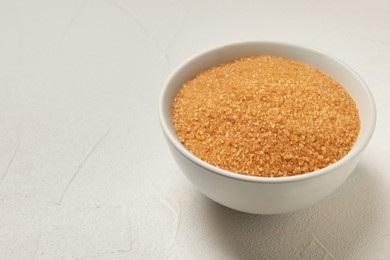 Photo of Brown sugar in bowl on white table. Space for text