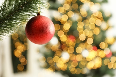 Photo of Beautiful holiday bauble hanging on Christmas tree against blurred lights