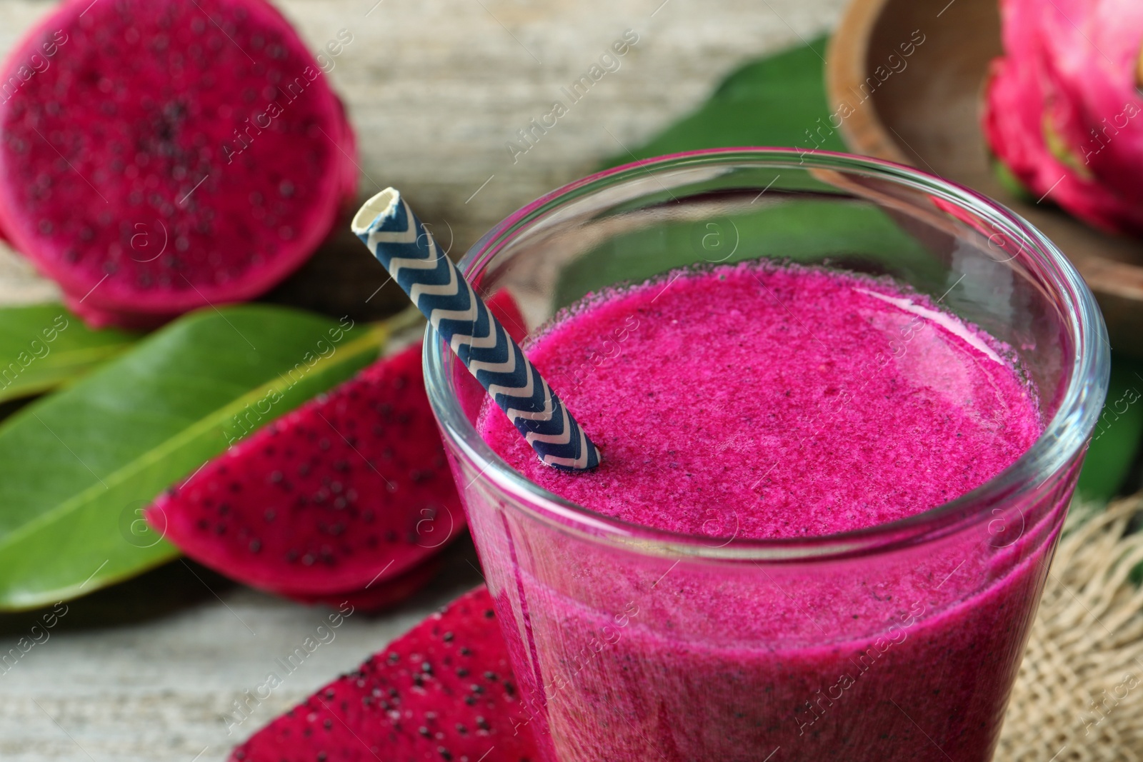 Photo of Glass of tasty pitahaya smoothie with straw on table, closeup view