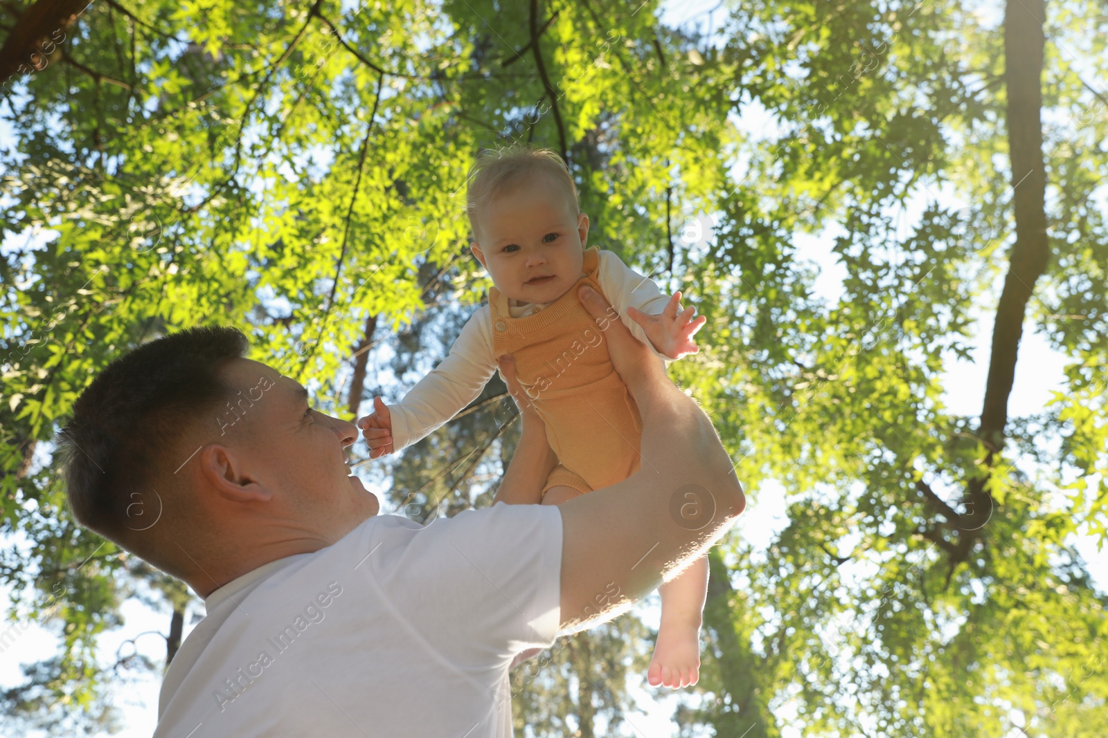 Photo of Father with his cute daughter spending time together in park on summer day, low angle view