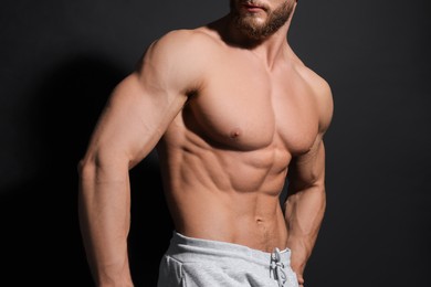 Photo of Muscular man showing abs on black background, closeup. Sexy body