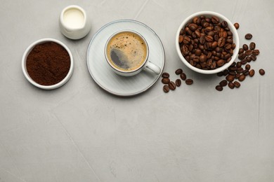 Flat lay composition with coffee grounds and roasted beans on light table, space for text