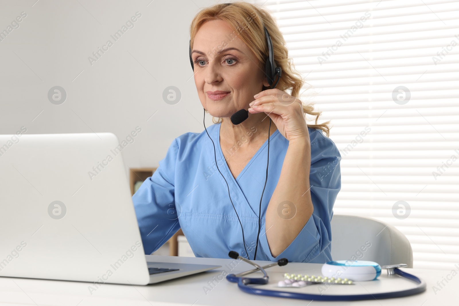 Photo of Doctor with laptop and headphones consulting patient in clinic. Online medicine concept