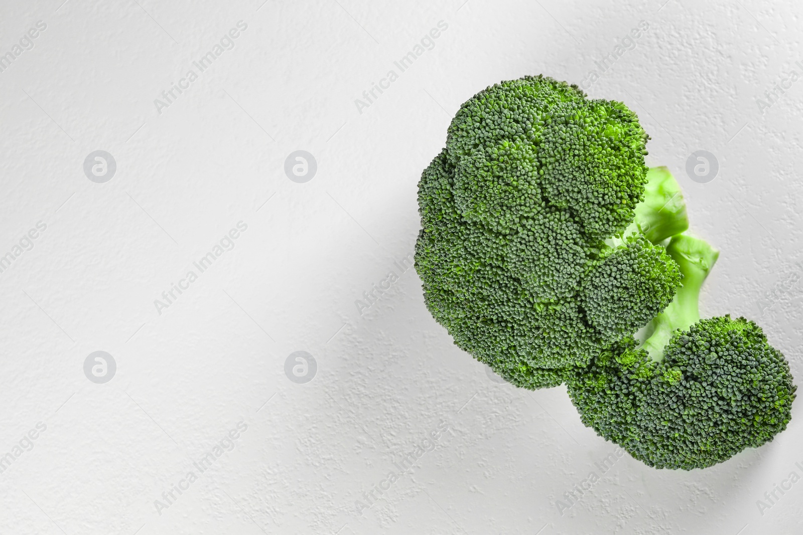 Photo of Fresh raw broccoli on white table, flat lay. Space for text