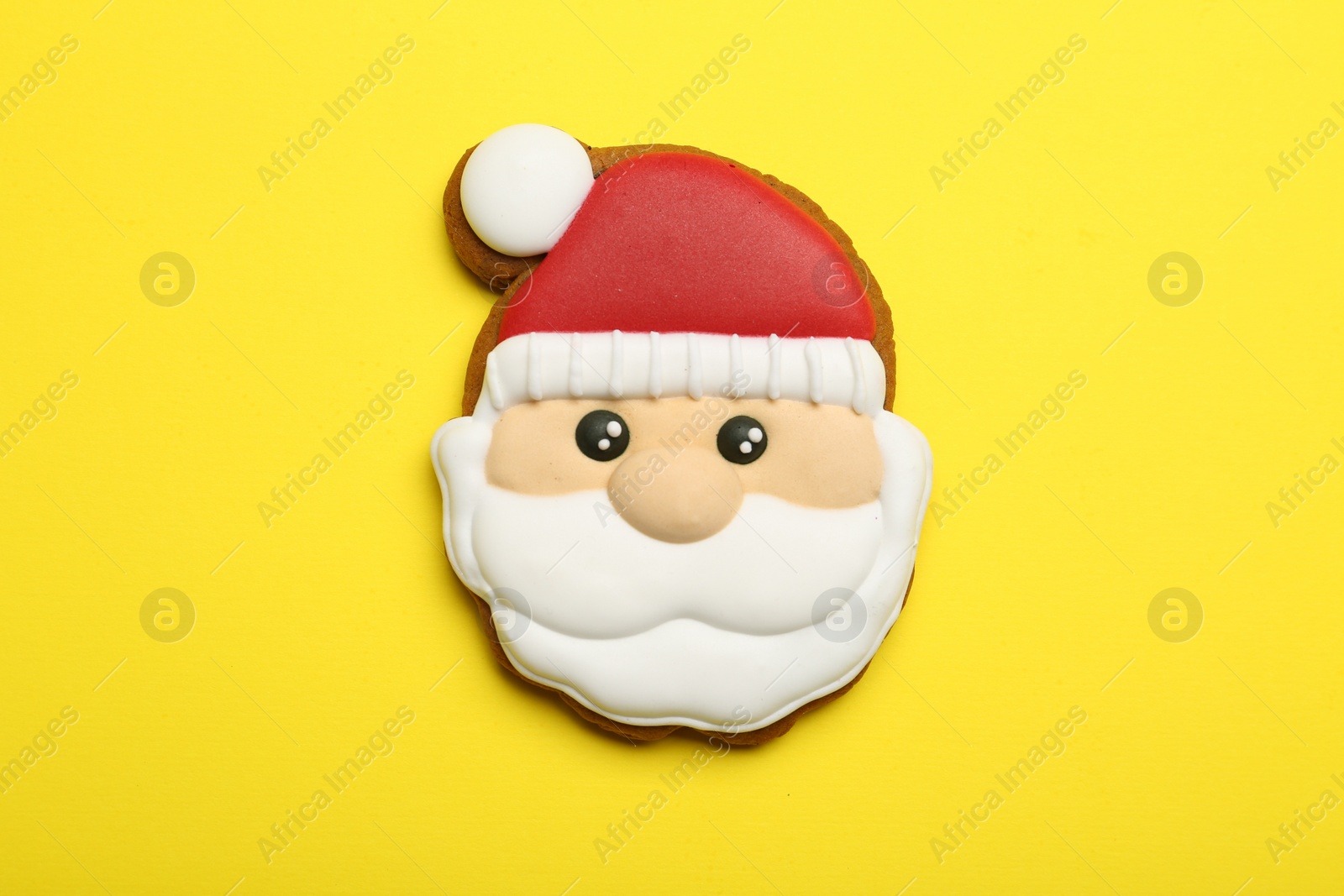 Photo of Christmas cookie in shape of Santa Claus on yellow background, top view