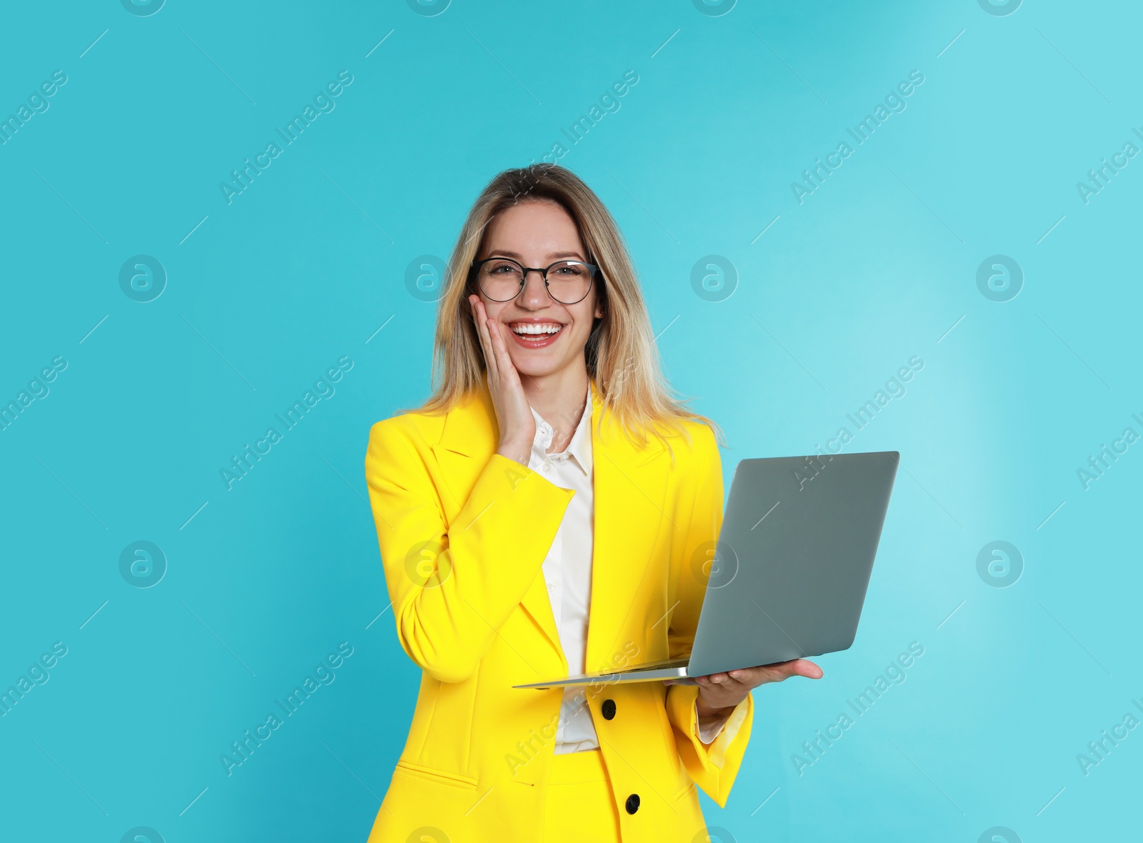 Photo of Young woman with modern laptop on light blue background