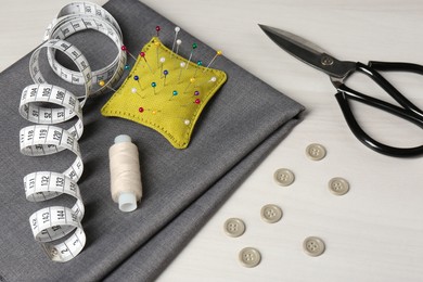 Set of sewing supplies and accessories on white table, above view