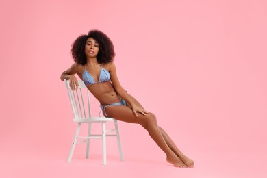 Photo of Beautiful woman in stylish bikini posing on chair against pink background