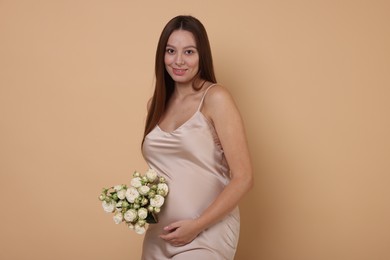 Beautiful pregnant woman in dress with bouquet of roses on beige background