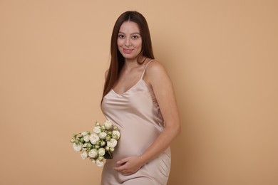 Photo of Beautiful pregnant woman in dress with bouquet of roses on beige background