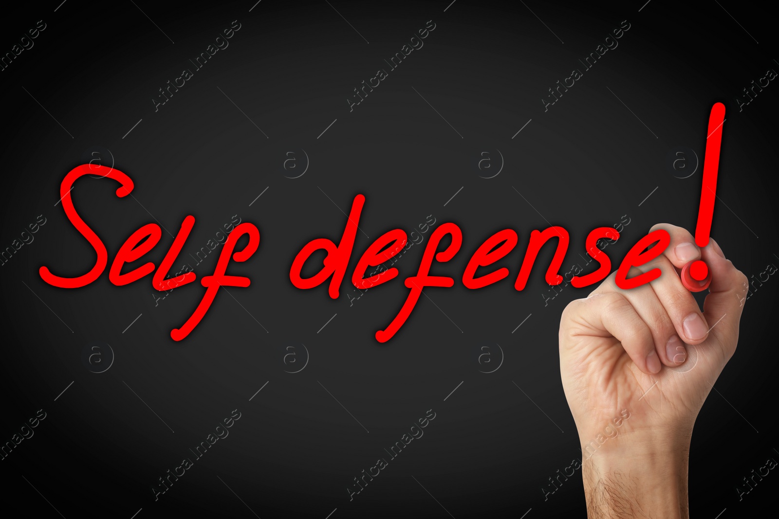Image of Man writing words Self Defense with marker on glass board against black background, closeup