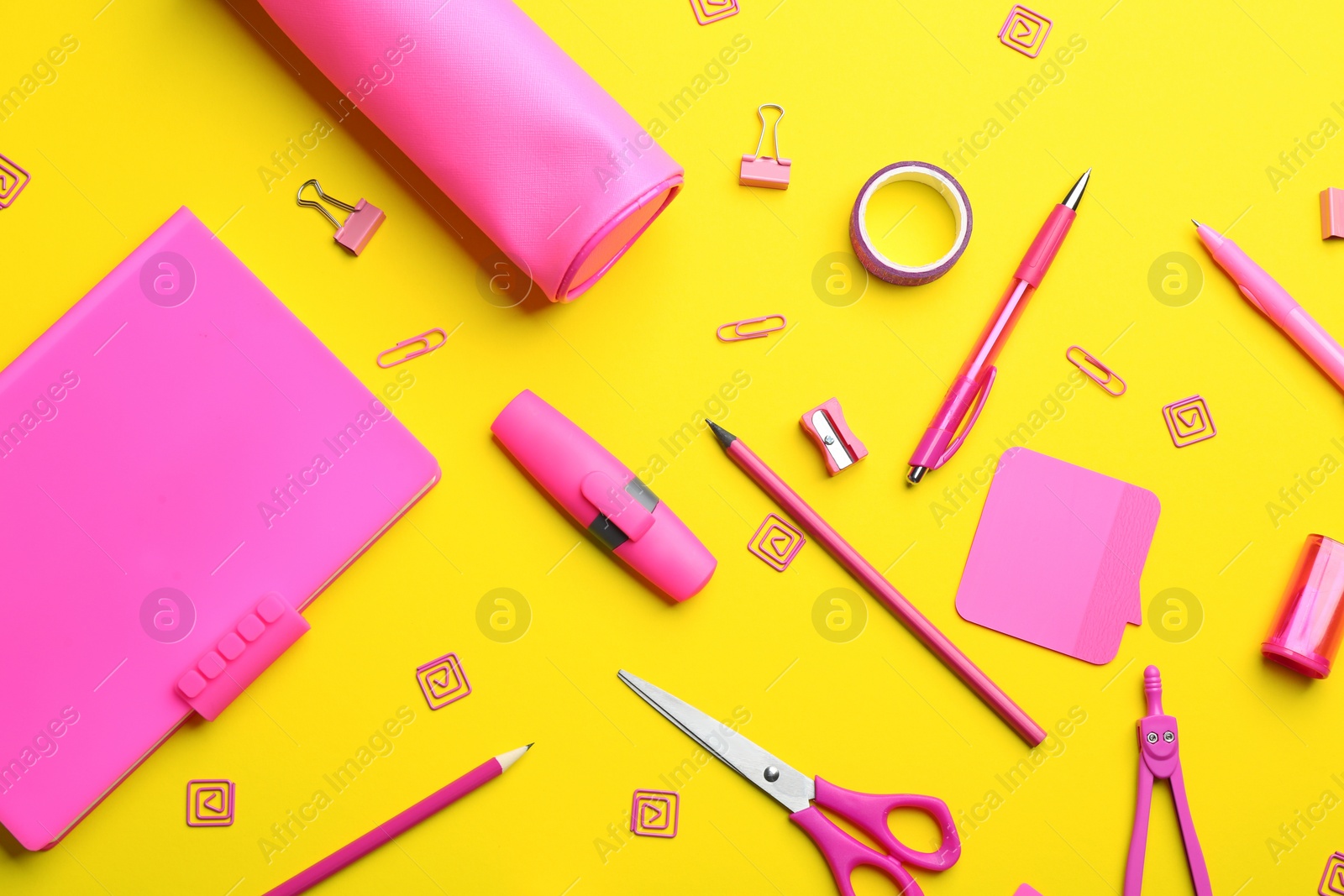 Photo of Pink school stationery on yellow background, flat lay