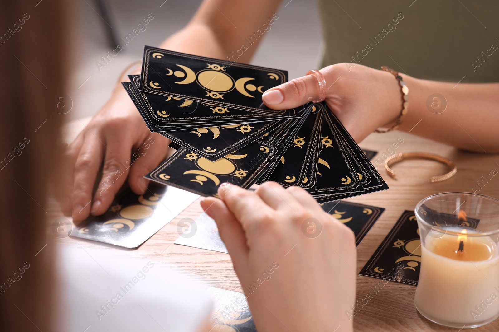 Photo of Woman pulling one tarot card at table indoors, closeup. Fortune telling