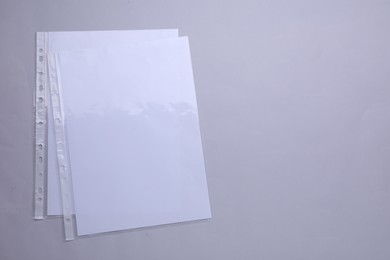 Photo of Punched pockets with paper sheets on light grey background, flat lay. Space for text