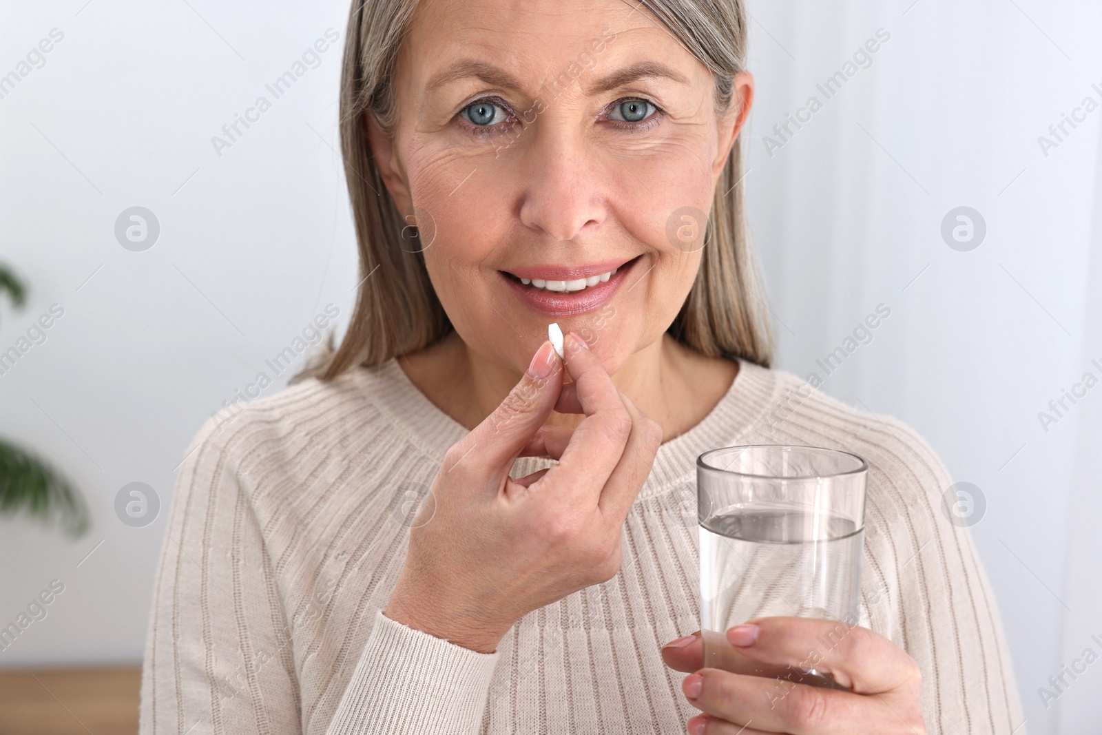 Photo of Beautiful woman taking vitamin pill at home