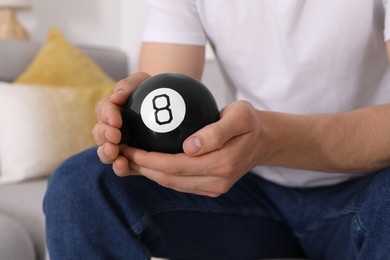 Man holding magic eight ball indoors, closeup