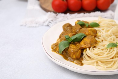 Delicious chicken, pasta with curry sauce and basil served on white table, closeup. Space for text