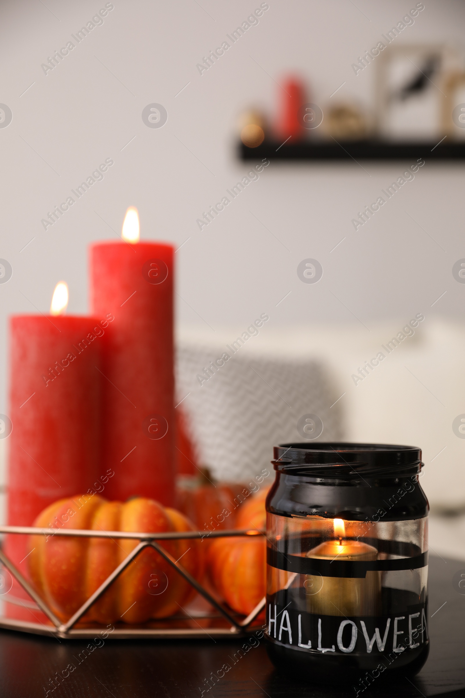 Photo of Burning candles on table in room. Idea for Halloween interior