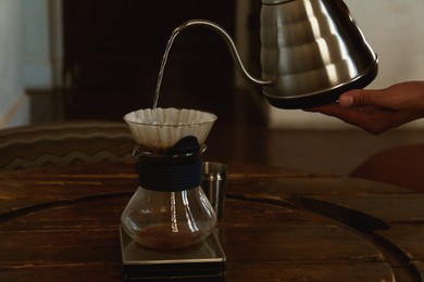 Barista pouring water from kettle into cup with coffee and wave dripper in cafe, closeup