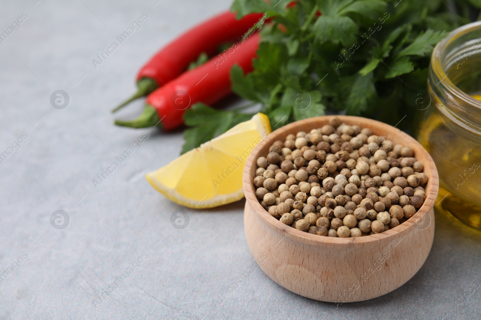 Photo of Aromatic peppercorns and different fresh ingredients for marinade on grey table. Space for text