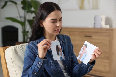Upset woman holding parts of torn photo at home. Divorce concept