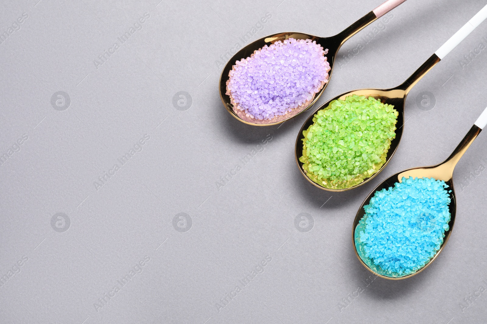 Photo of Spoons with colorful sea salt on light grey table, flat lay. Space for text