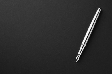 Photo of Stylish silver fountain pen on black background, top view. Space for text