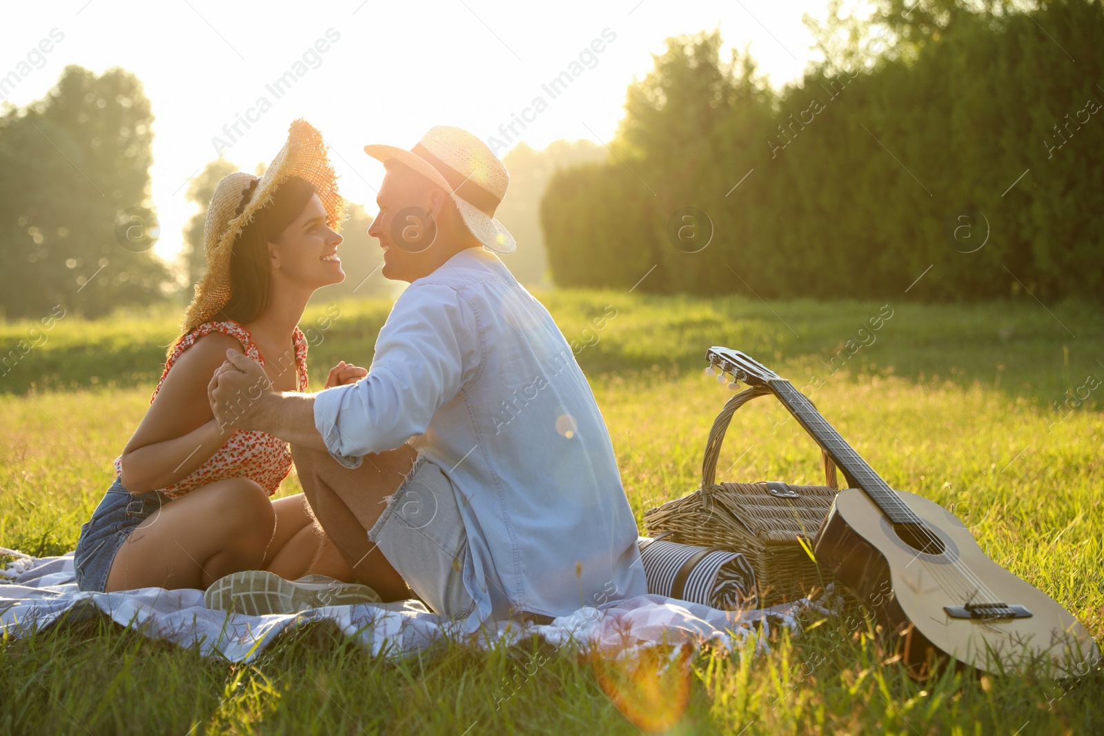 Photo of Happy couple with guitar and picnic basket in park on sunny day