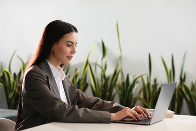 Photo of Woman using modern laptop at desk in office
