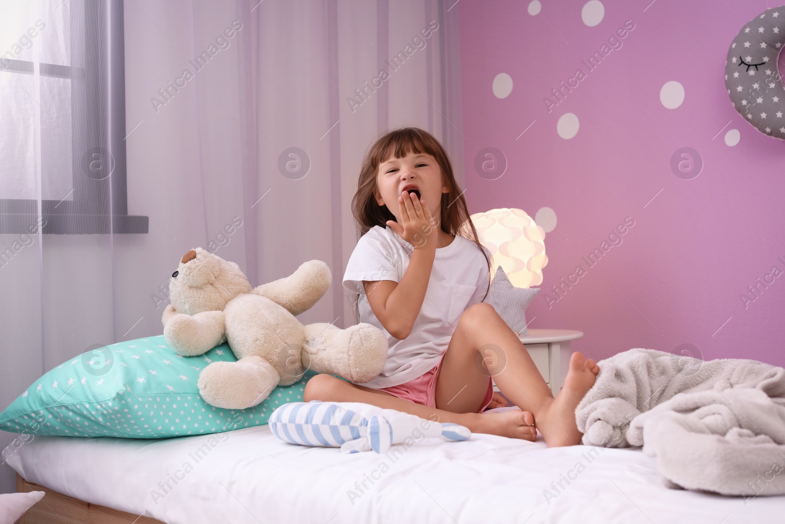 Photo of Little girl yawning on bed at home. Time to sleep