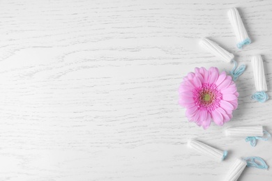 Photo of Flower and tampons on white wooden background, flat lay with space for text. Gynecological care