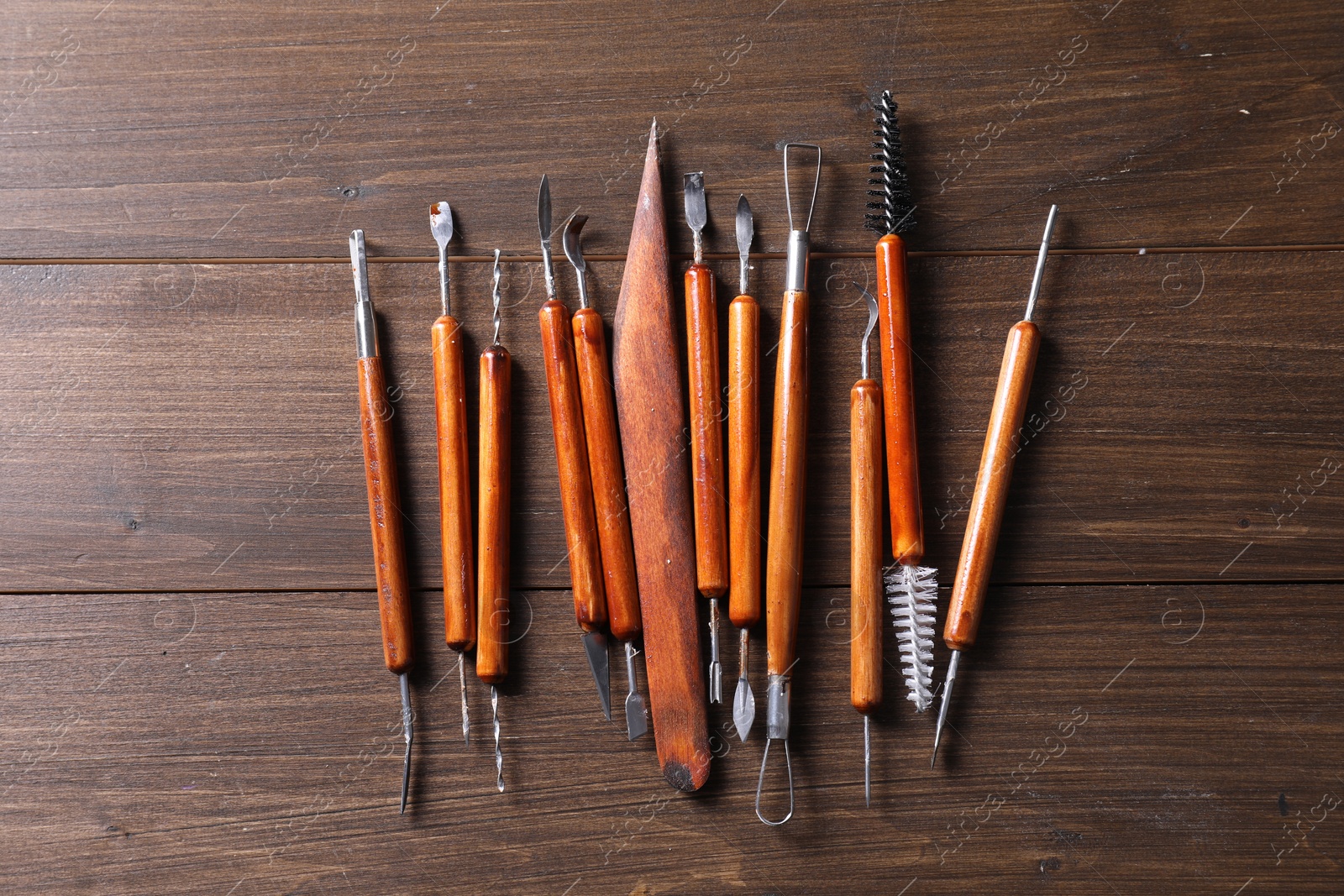 Photo of Set of different clay crafting tools on wooden table, flat lay