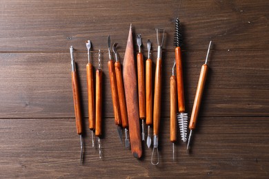 Photo of Set of different clay crafting tools on wooden table, flat lay