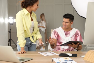 Photo of Professional retoucher with colleague working at desk in photo studio