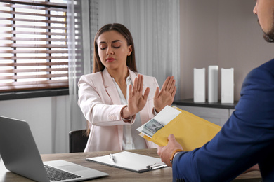 Businesswoman rejecting bribe at table in office