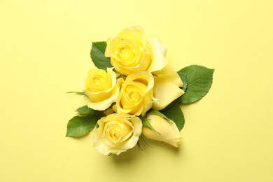 Beautiful roses on yellow background, flat lay