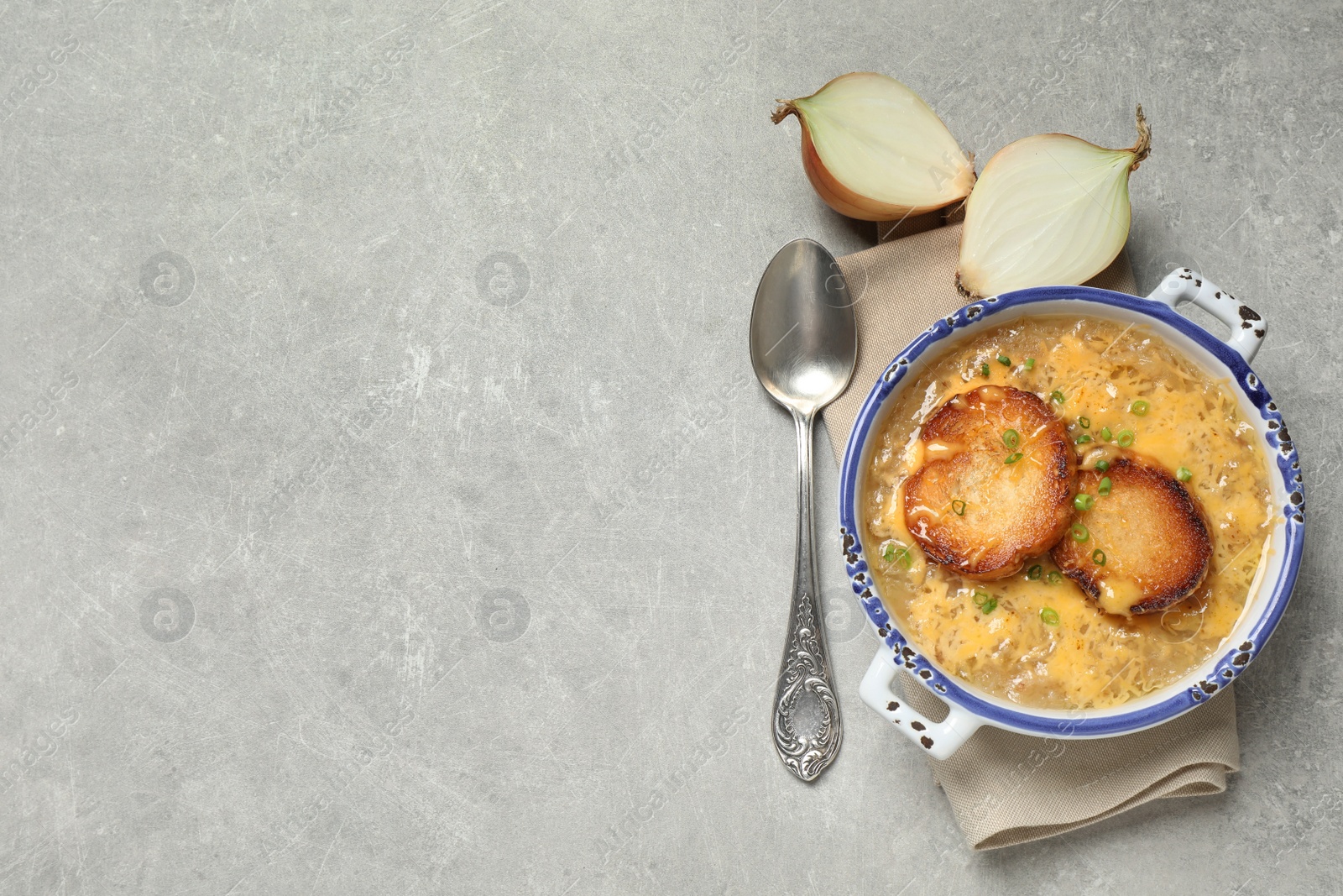 Photo of Tasty homemade french onion soup served on grey table, flat lay. Space for text