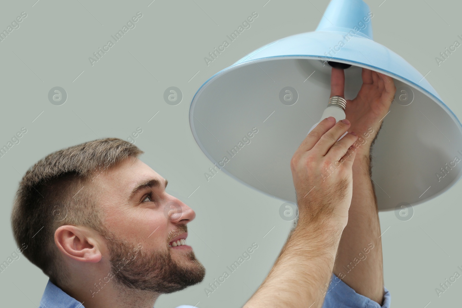 Photo of Man changing light bulb in lamp indoors