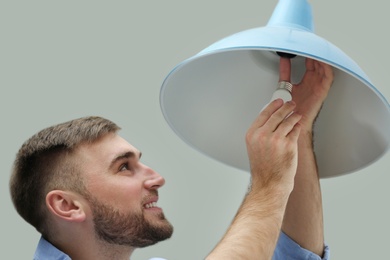 Man changing light bulb in lamp indoors