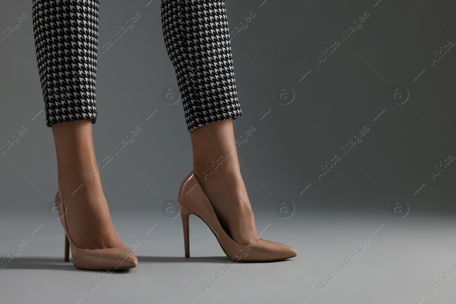 Photo of Businesswoman in beige shoes on grey background, closeup. Space for text