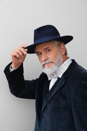 Attractive senior man in stylish hat on light background