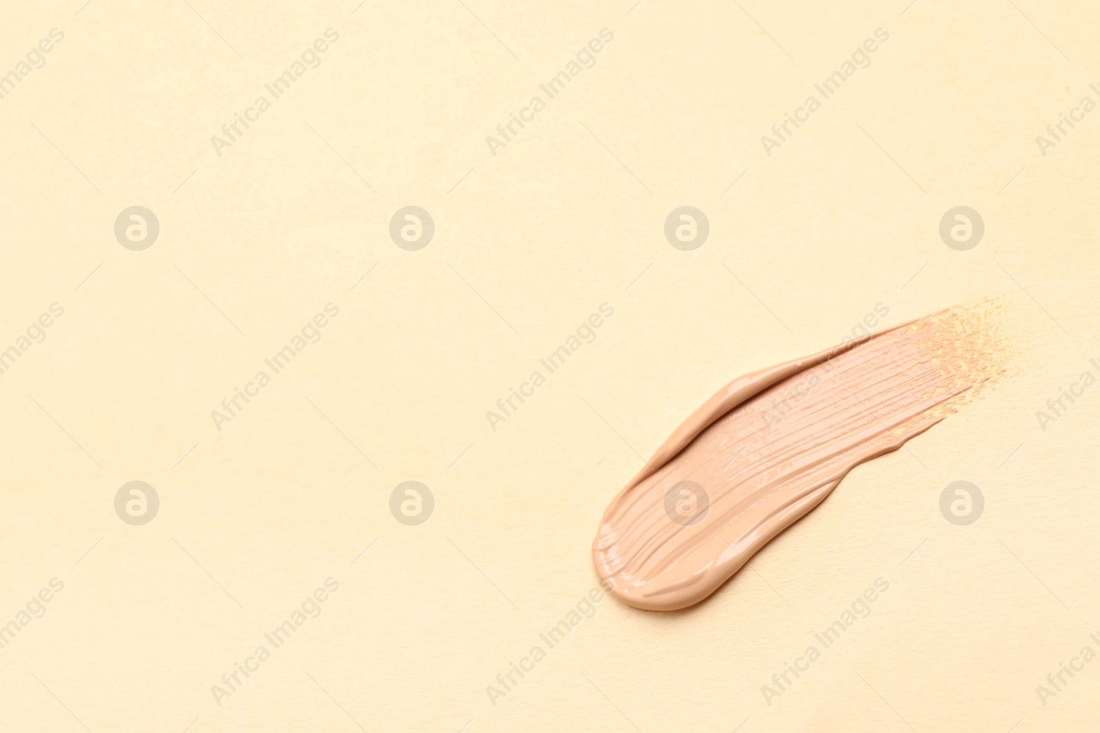 Photo of Smear of skin foundation on beige background. Space for text