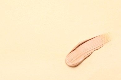 Photo of Smear of skin foundation on beige background. Space for text