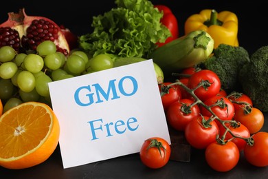 Photo of Tasty fresh GMO free products and paper card on black table