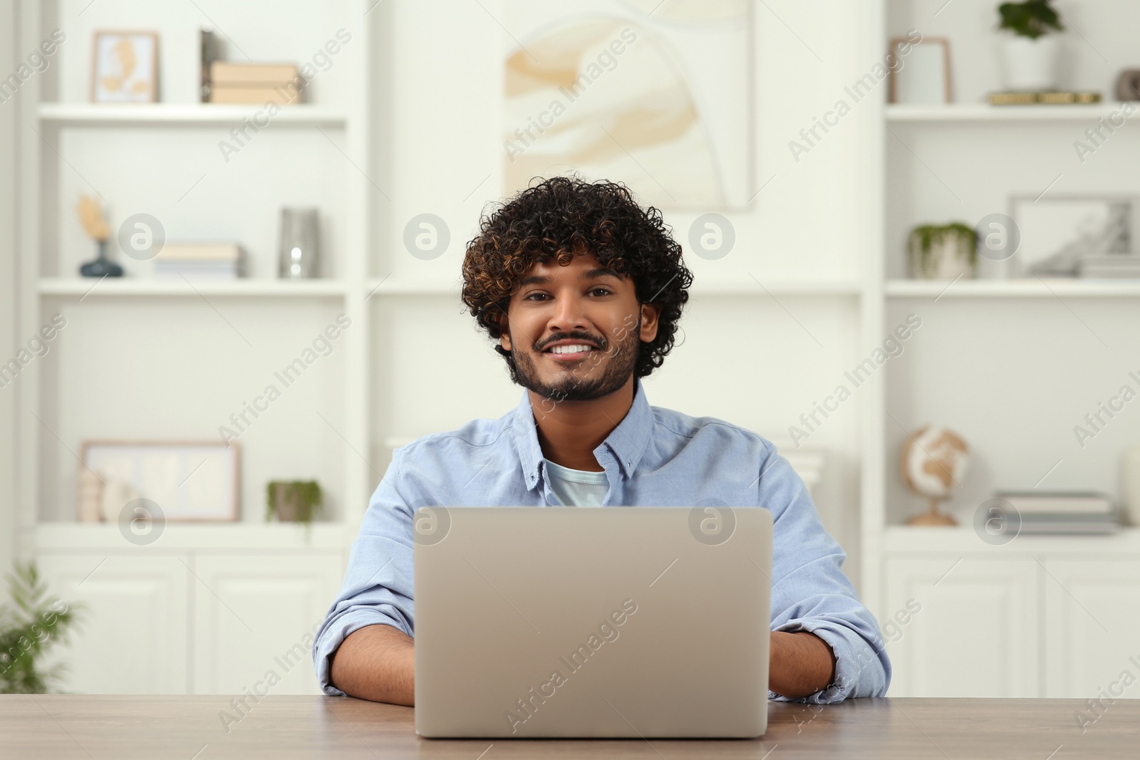 Photo of Handsome smiling man using laptop in room