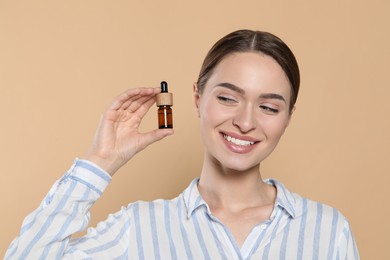 Photo of Young woman with bottle of essential oil on beige background