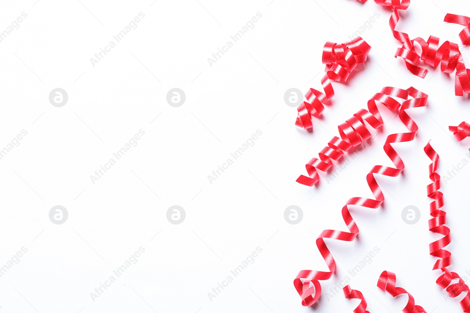 Photo of Red serpentine streamers on white background, top view