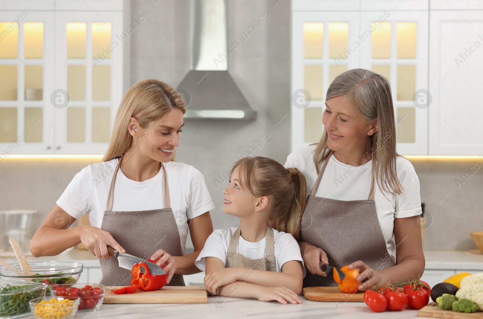 Photo of Three generations. Happy grandmother, her daughter and granddaughter cooking together in kitchen