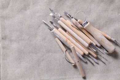 Photo of Set of different clay crafting tools on grey fabric, top view. Space for text